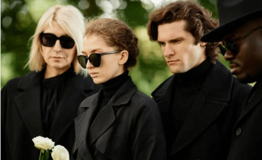 Due donne e due uomini dall'atteggiamento triste in completo e occhiali scuri