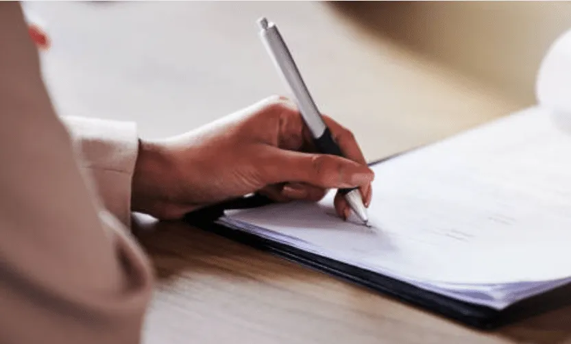 Mano di donna che impugna una penna e scrive su un foglio