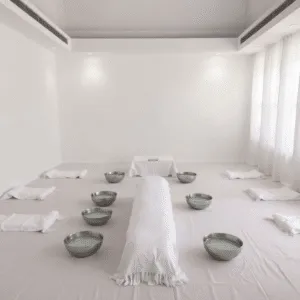 Una stanza tranquilla preparata per un funerale islamico, con panni bianchi e ciotole d’acqua disposte per il lavaggio rituale (ghusl) della salma, in un’atmosfera calma e rispettosa con luce soffusa.